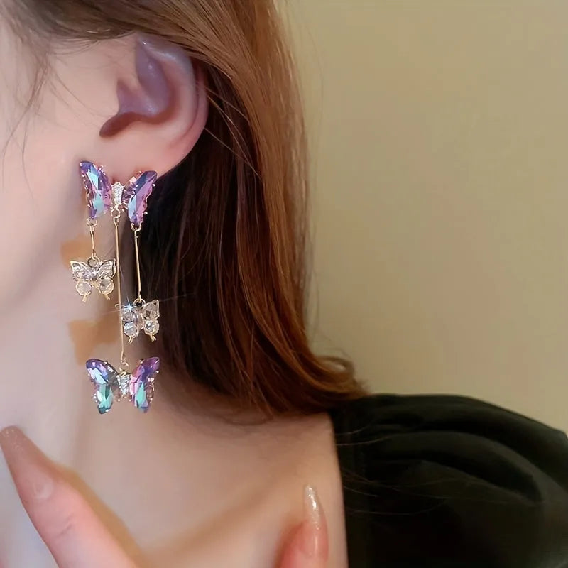 Silver electroplated alloy drop earrings with a blue purple butterfly charm and crystal flower details on a tassel.
