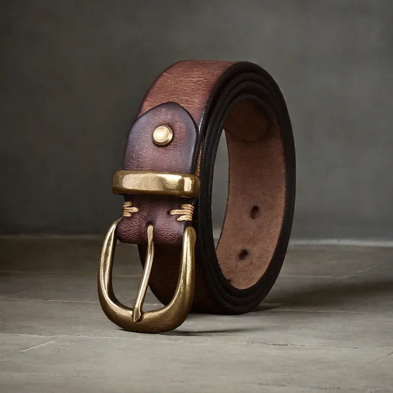 Men's black genuine cowhide leather belt with copper pin buckle on a jeans background.