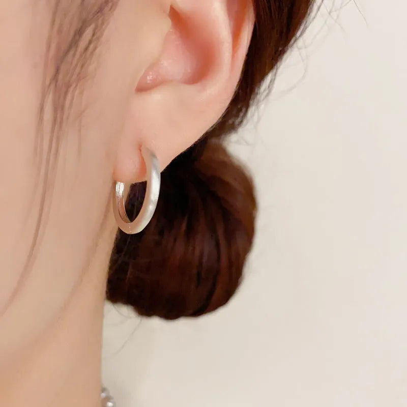 Geometric gold-plated ear clip with round eyelet detail on white background