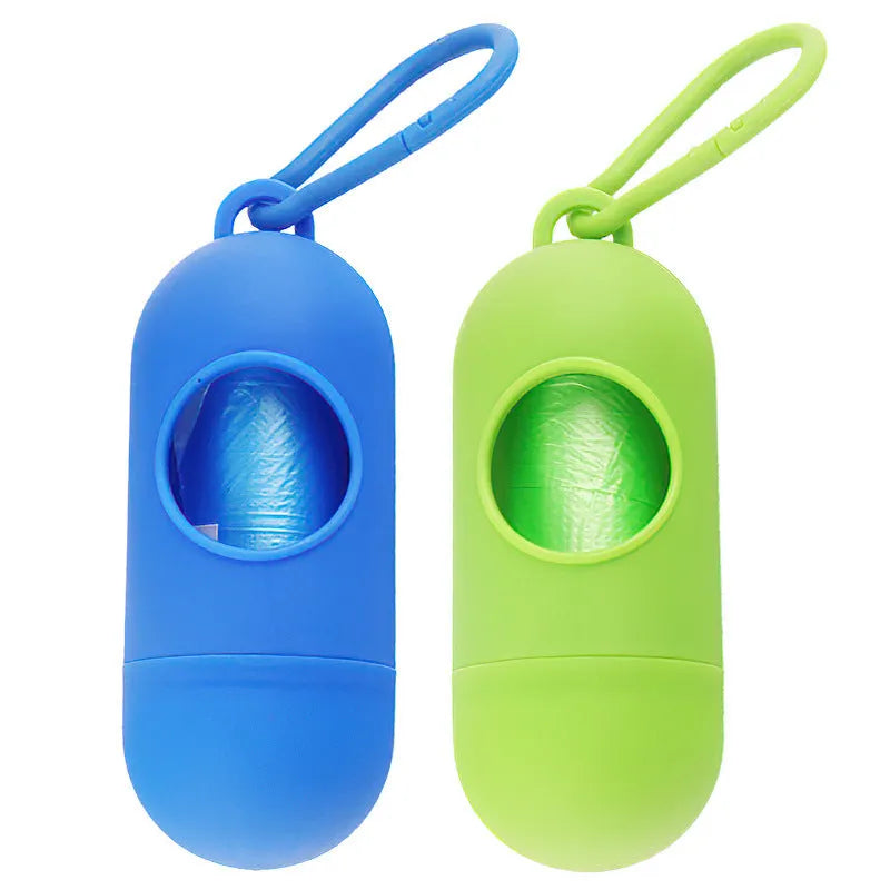 Compact black dog poop bag holder with Velcro strap and metal side hook, shown next to a roll of waste bags.