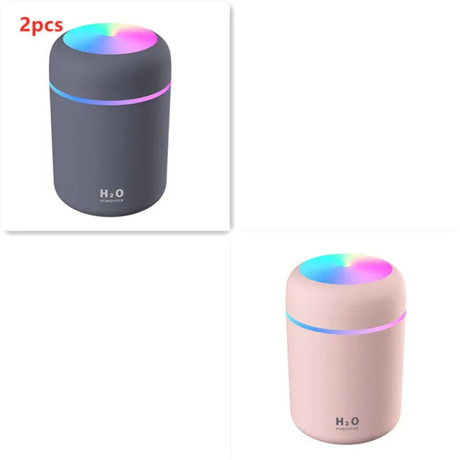 Pink USB desktop humidifier with coloured lights and water tank on a wooden desk