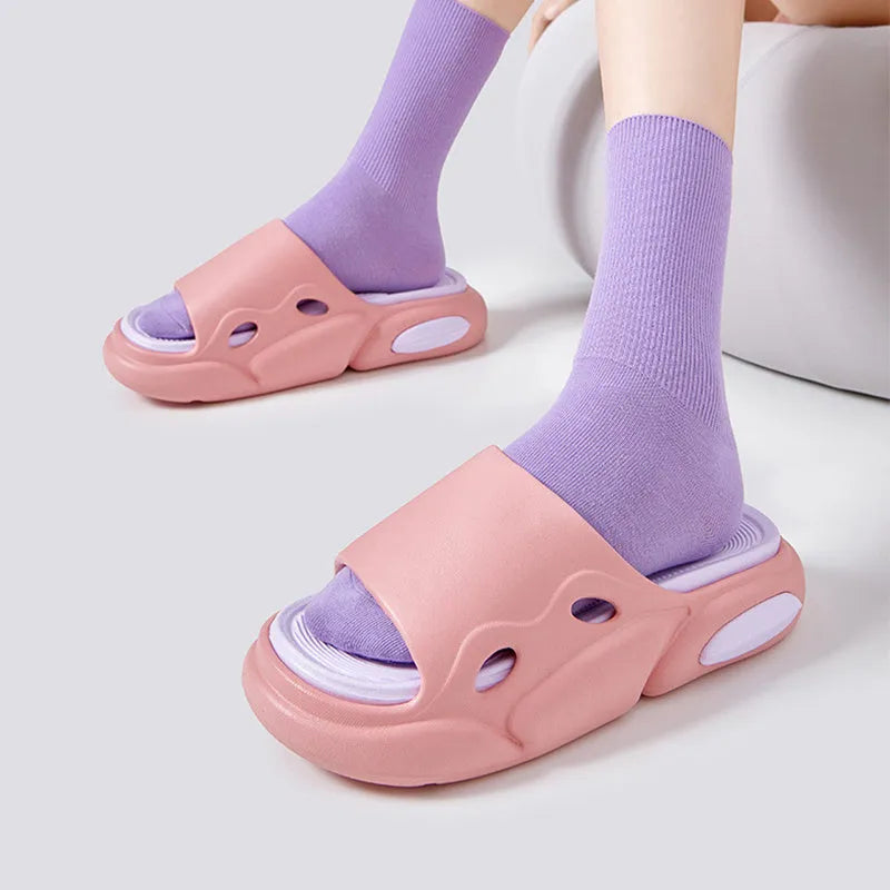 Two-colour thick-soled EVA slippers for couples on a floor, showing pink and purple or black and white colour options.