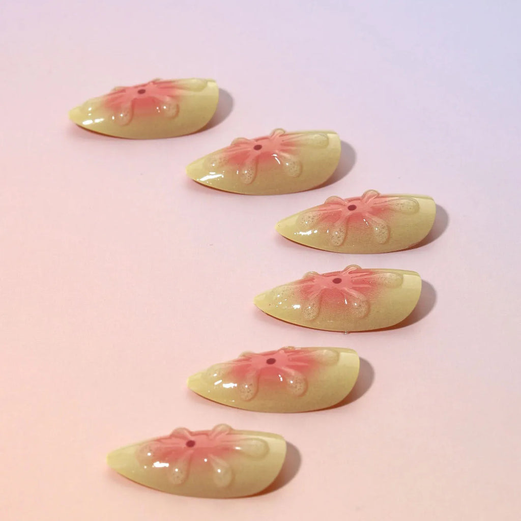 Set of simple fake nails with pink and white cartoon 3D flower charms on a wearable armour base.