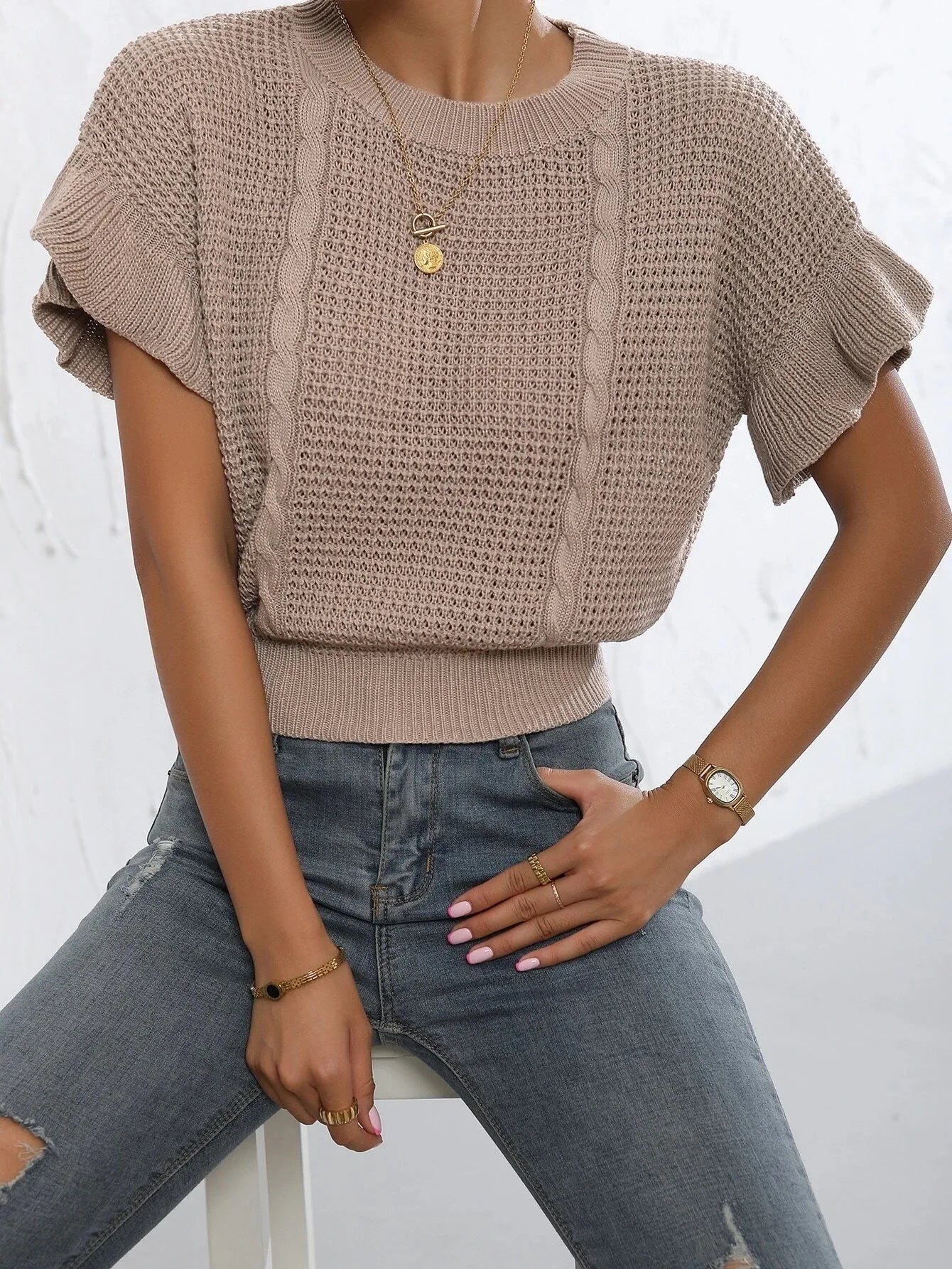 Loose-fitting white knitted pullover sweater with textured ruffled short sleeves on a model.