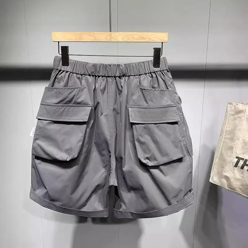 Man wearing large size black loose-fit work shorts with pockets, showing above-the-knee length.