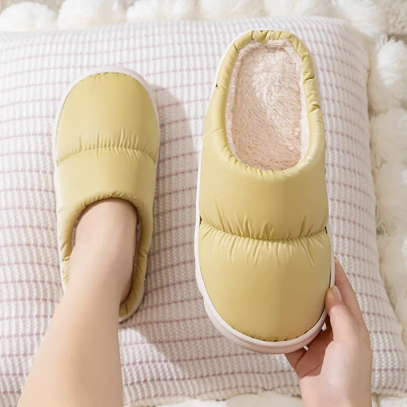 Blue down cotton indoor slippers with thick rubber sole and plush lining, shown on a wooden floor.