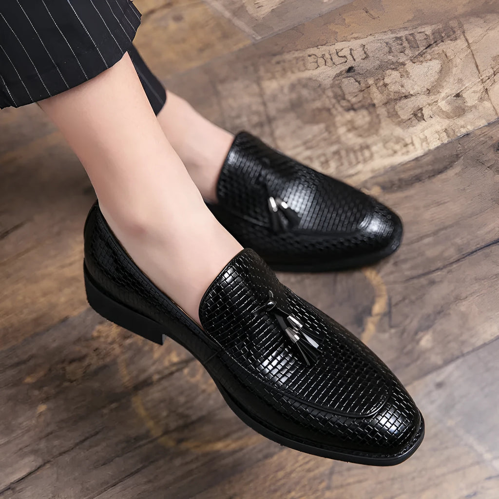 Men's black pointed toe slip-on shoes with a tassel detail on the vamp