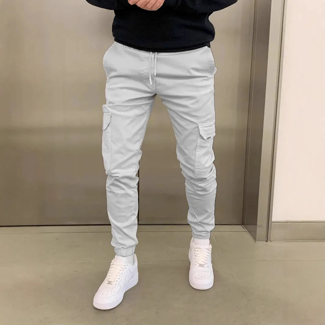Man wearing loose light blue casual trousers with patch pockets and an elasticated waist.