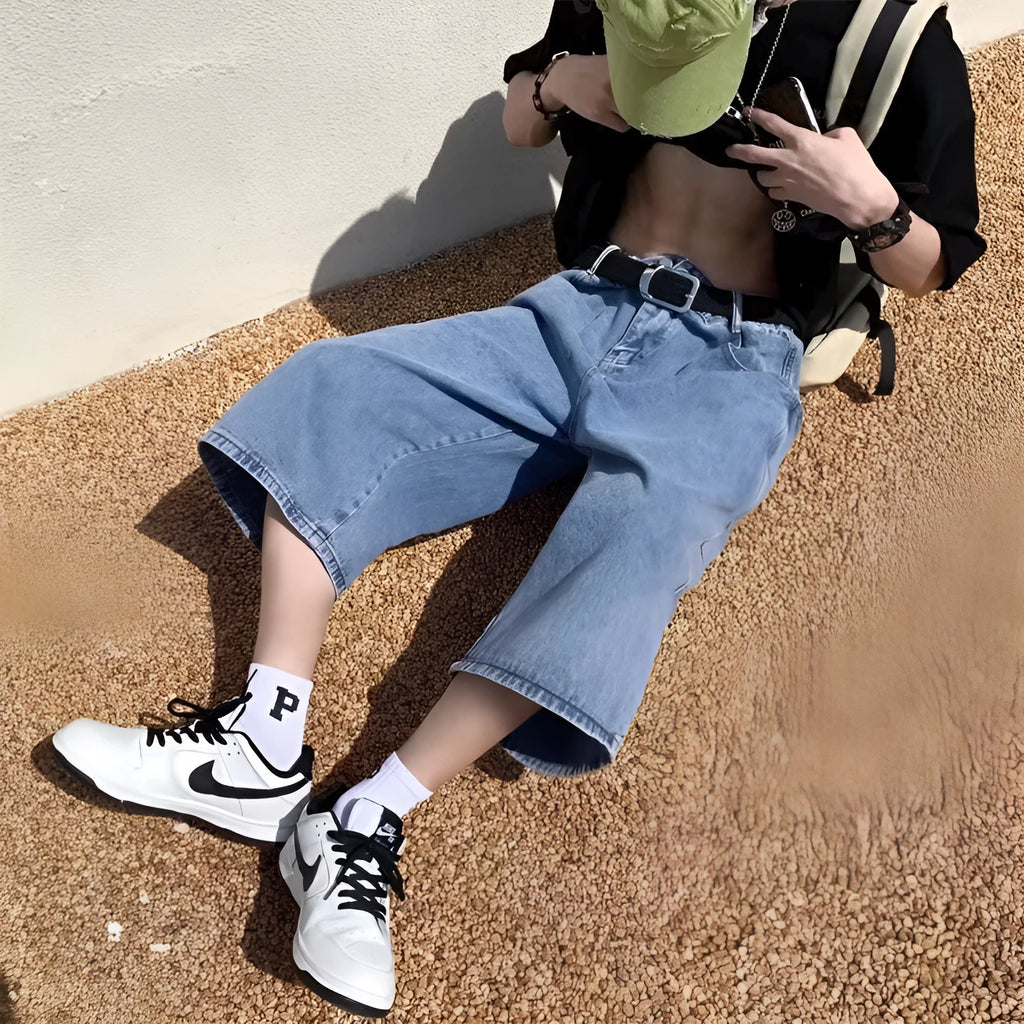 Man wearing blue washed denim high waist pirate shorts with a cropped, straight leg