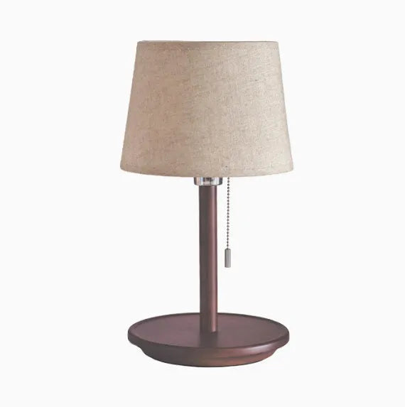 Walnut-colour solid wood desk lamp with a white fabric shade on a wooden table.