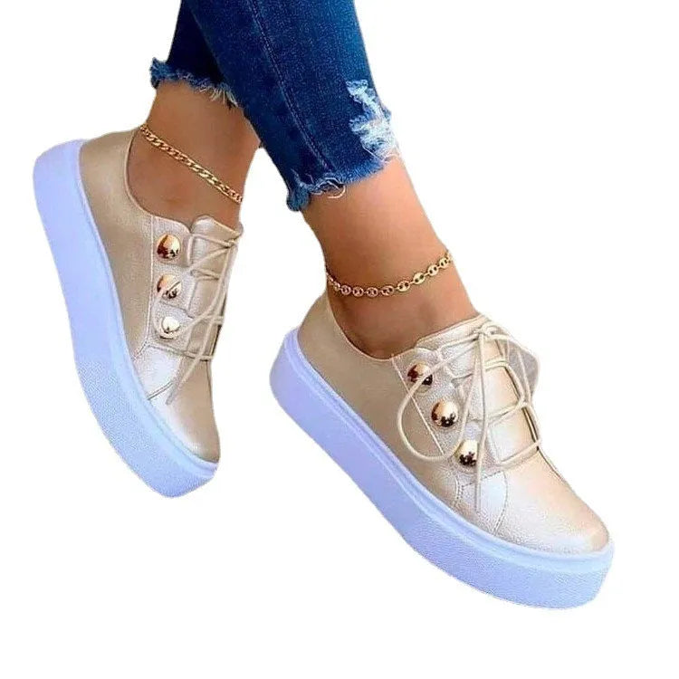 Women's white lace-up flat sneakers with silver rivet details on the sides and a round toe.