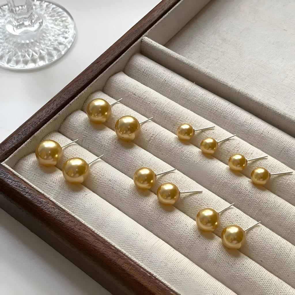 A pair of large geometric pearl stud earrings with an eight-point star detail on silver settings.