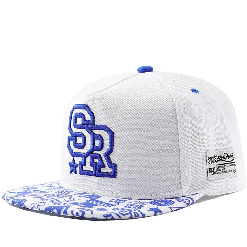 Cotton baseball cap with embroidered letters in black or white, showing adjustable strap.