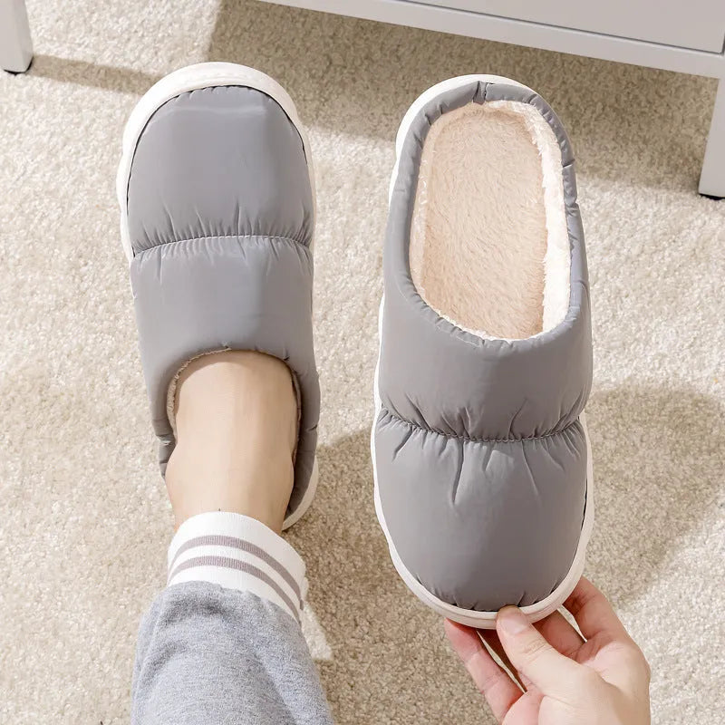 Blue down cotton indoor slippers with thick rubber sole and plush lining, shown on a wooden floor.