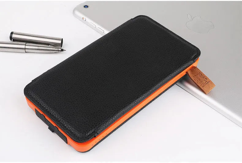 Black solar power bank with a solar panel, LED light, USB ports, and a soft leather casing.