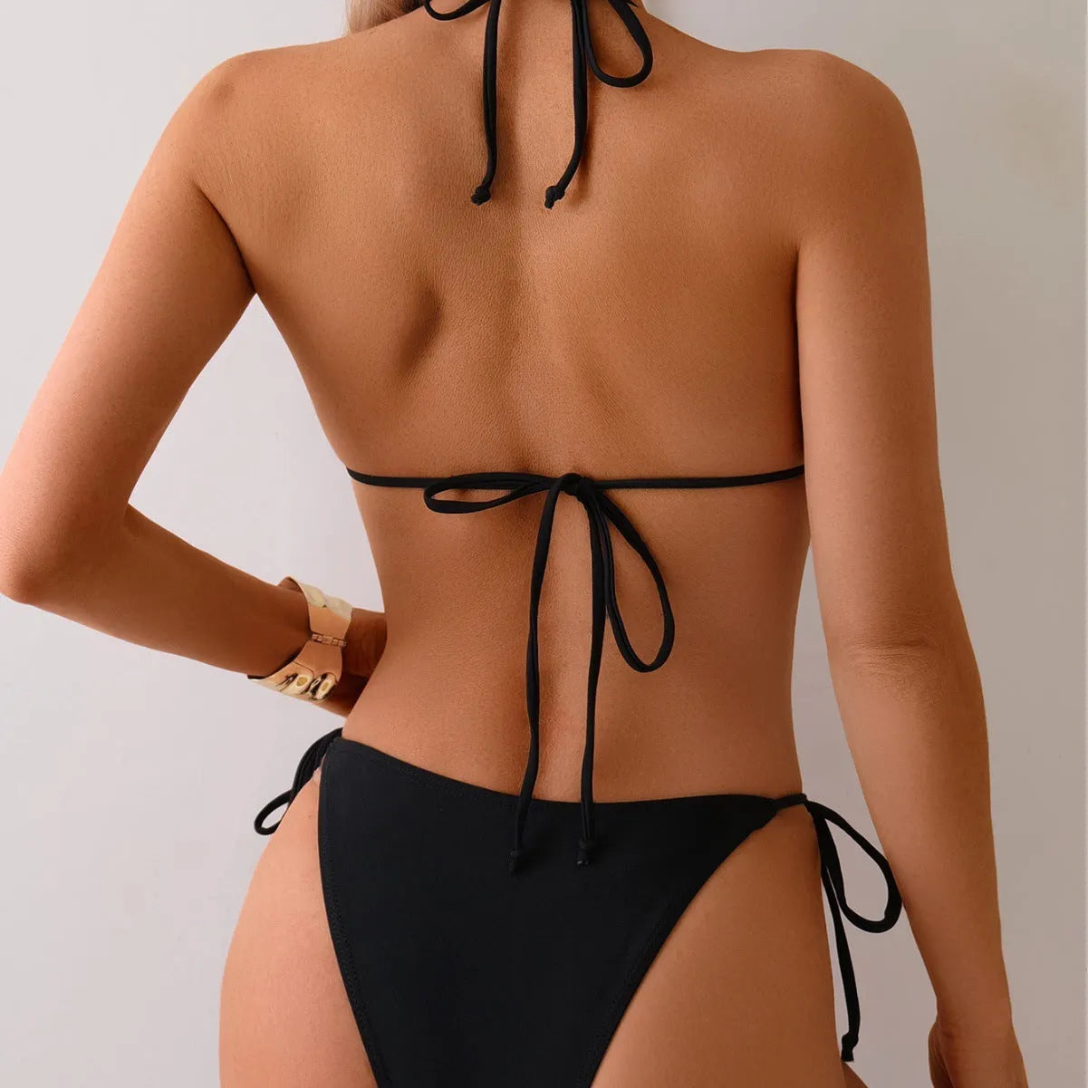 Black women's bikini swimsuit with metal bead split design on a mannequin.