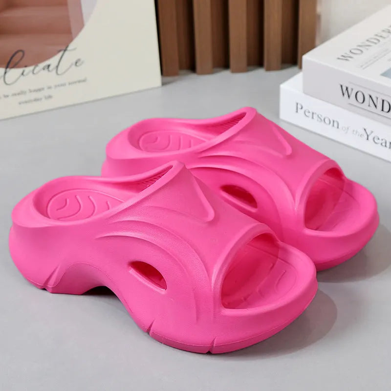 Women's thick-soled EVA slippers in rose red colour on a sandy beach background.