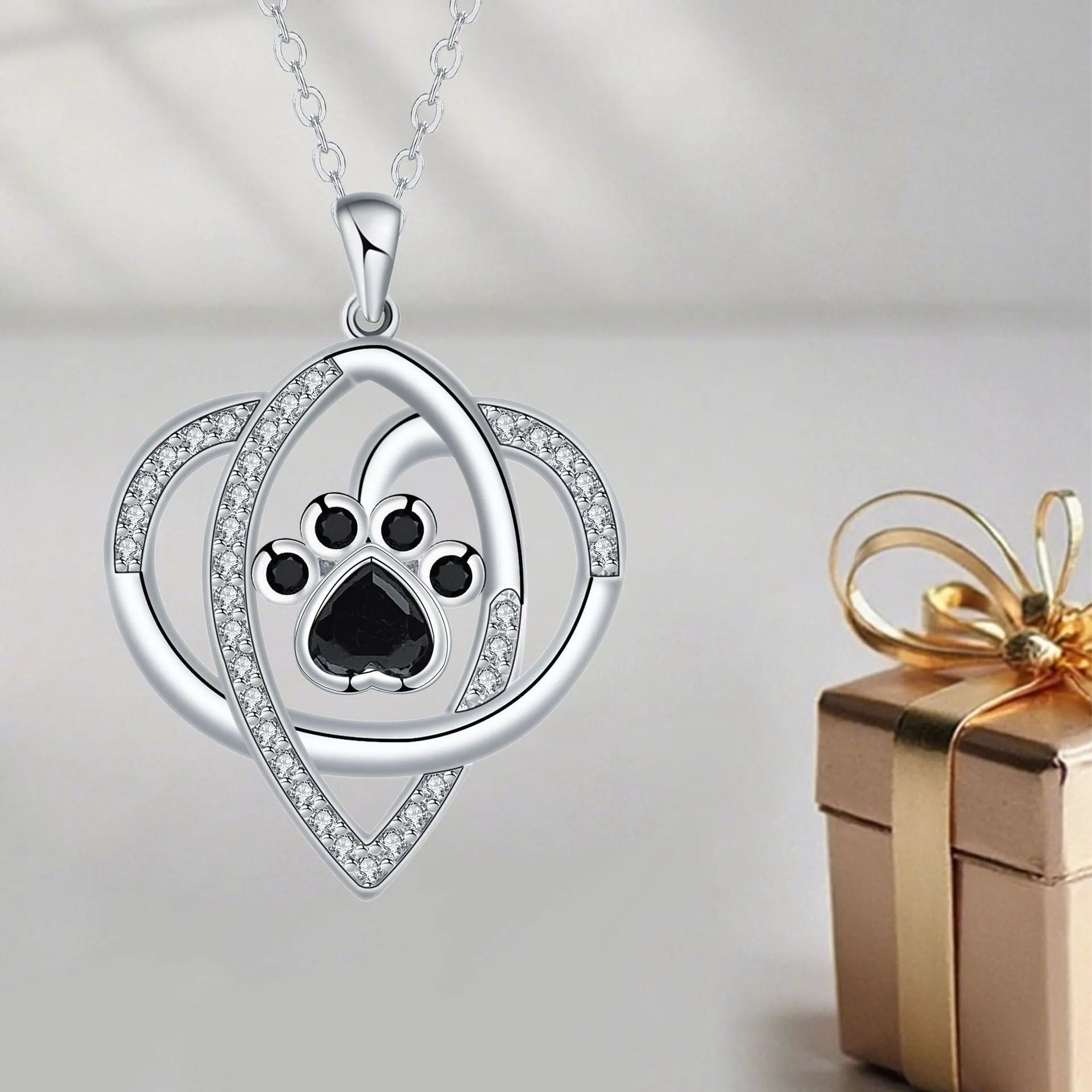 Close-up of a copper necklace pendant showing detailed cat and dog paw prints on a cross chain.