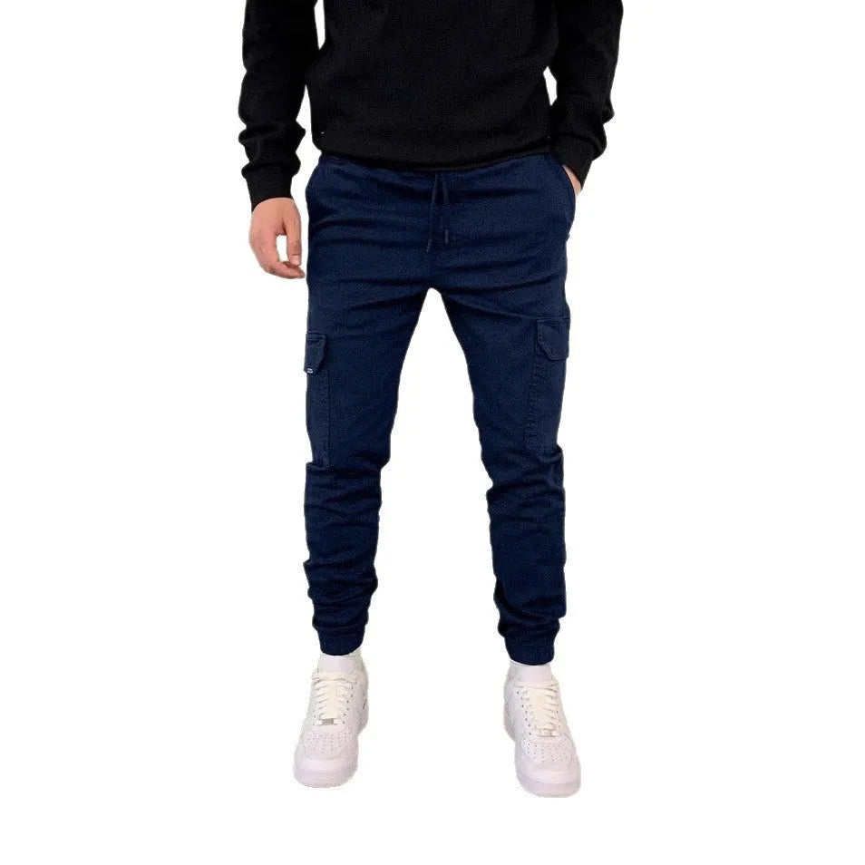 Man wearing loose light blue casual trousers with patch pockets and an elasticated waist.