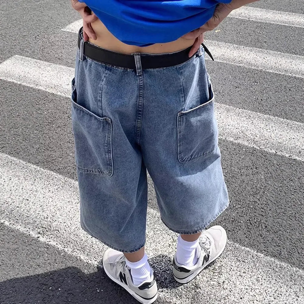 Man wearing blue washed denim high waist pirate shorts with a cropped, straight leg