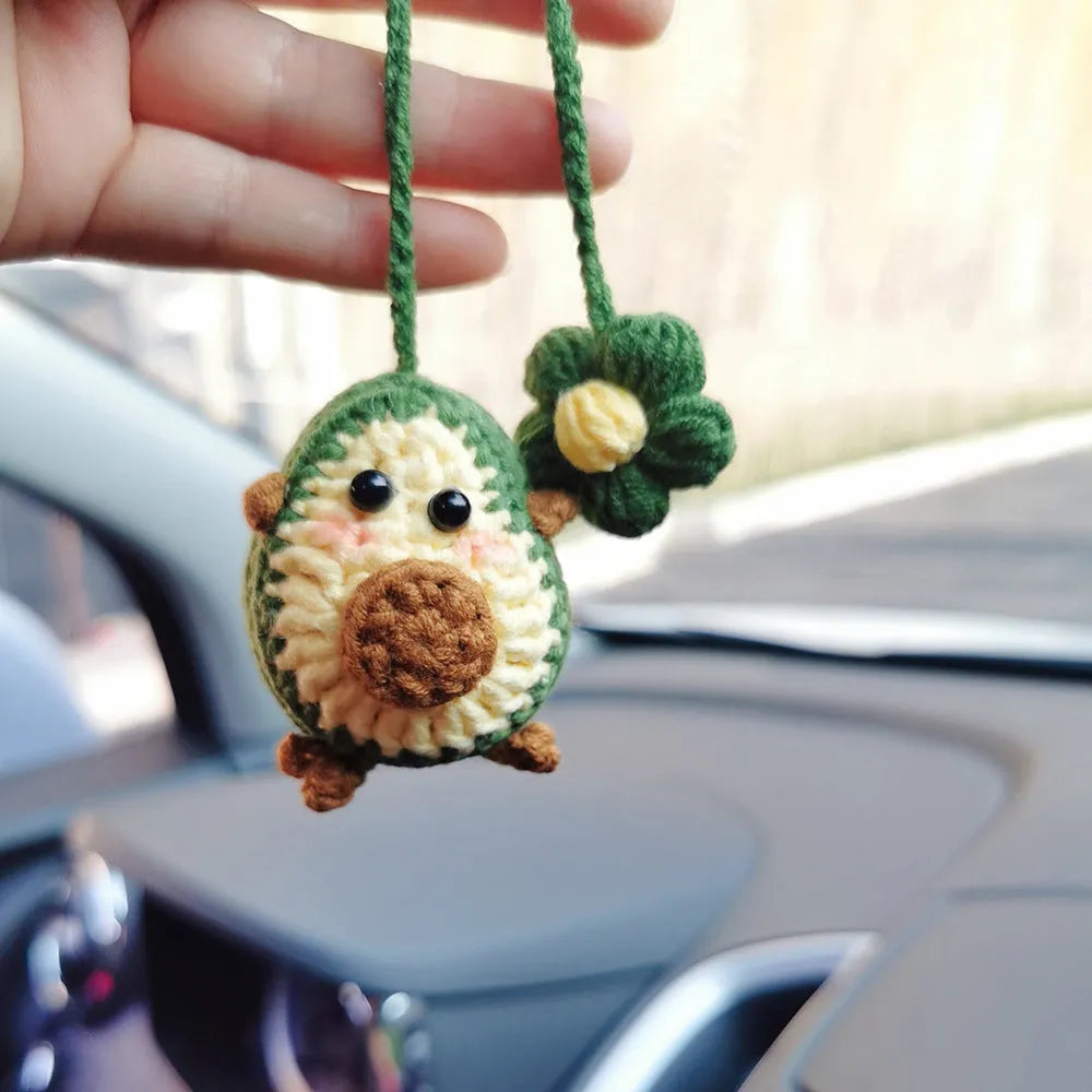 Handmade crocheted avocado flower car pendant in wool with rainbow colours hanging in vehicle