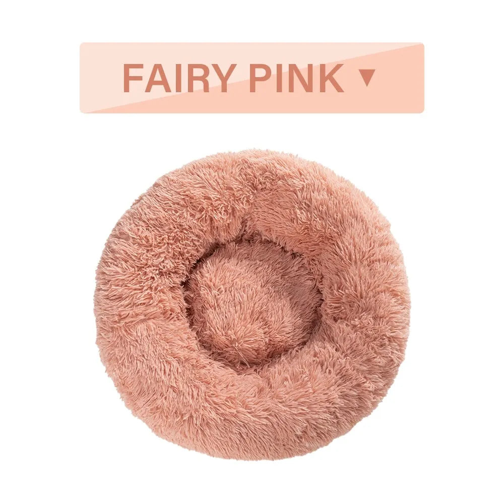 Fluffy donut-shaped dog bed in long plush fabric, shown in a light grey colour with a raised edge.