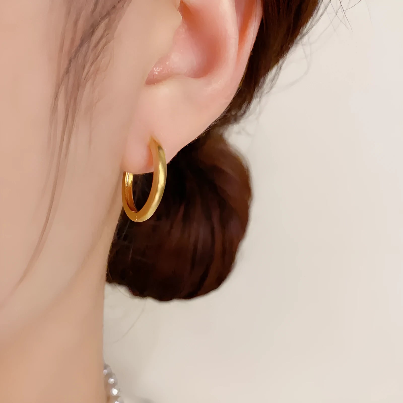 Geometric gold-plated ear clip with round eyelet detail on white background