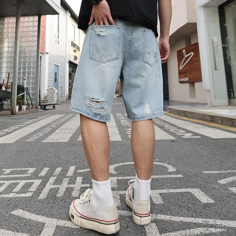 Light blue ripped denim shorts with distressed details, loose straight leg cut on a neutral background.