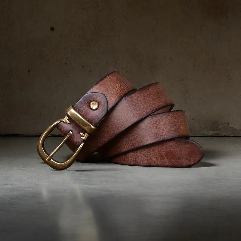 Men's black genuine cowhide leather belt with copper pin buckle on a jeans background.