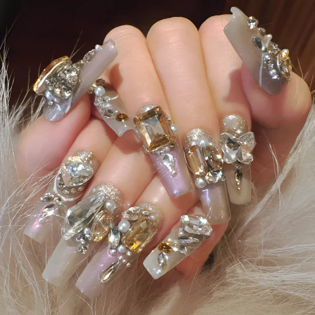False nail patches with large rhinestones on card, shown with jelly adhesive pot and nail tools.