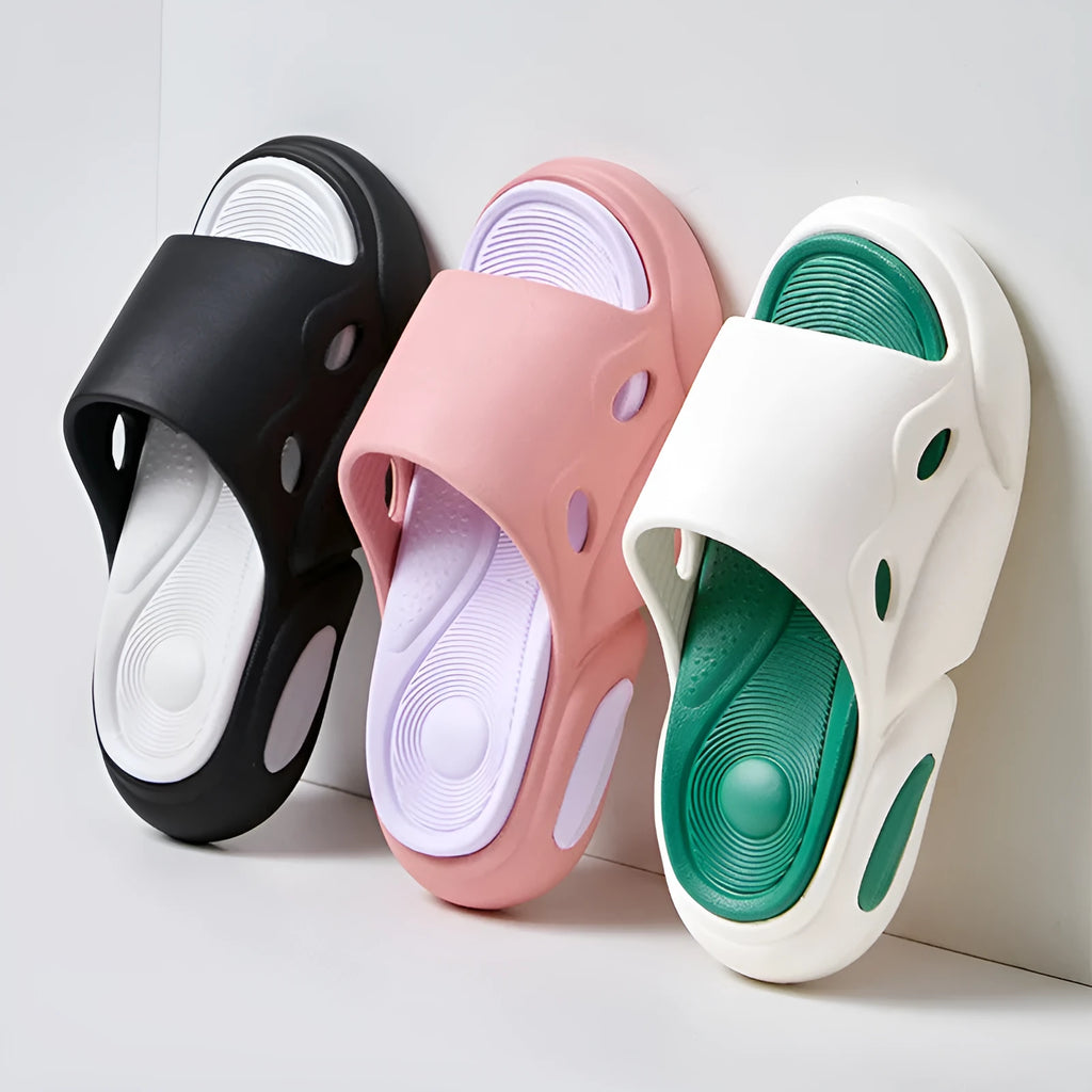 Two-colour thick-soled EVA slippers for couples on a floor, showing pink and purple or black and white colour options.