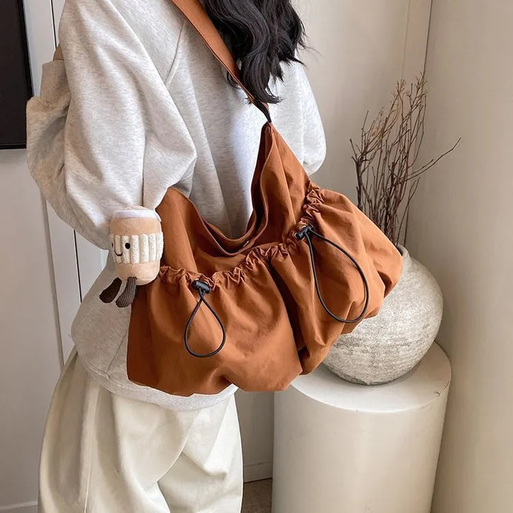 Ultra-light pleated green crossbody cloth bag lying flat, showing its split pocket and foldable design.