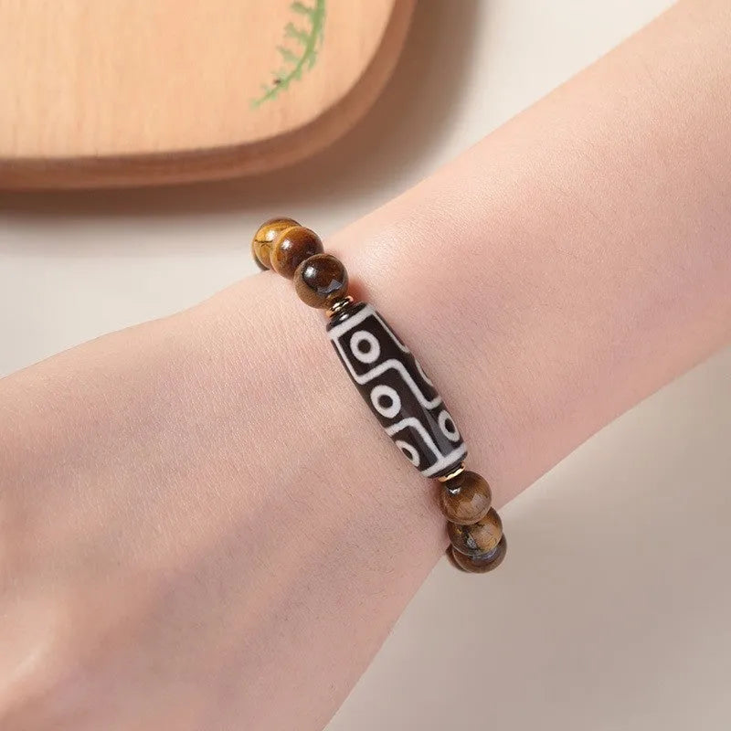 Close-up of a single-circle beaded Buddha rosary bracelet with tigereye dzi patterns on brown beads.
