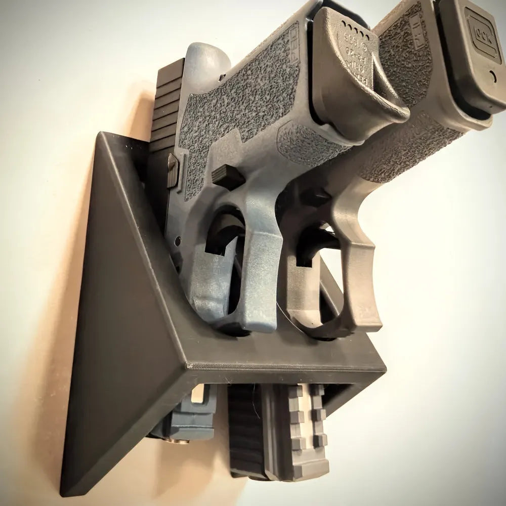 Black plastic punk-style pistol display stand for airsoft guns, measuring 10.85 by 7.6 cm.