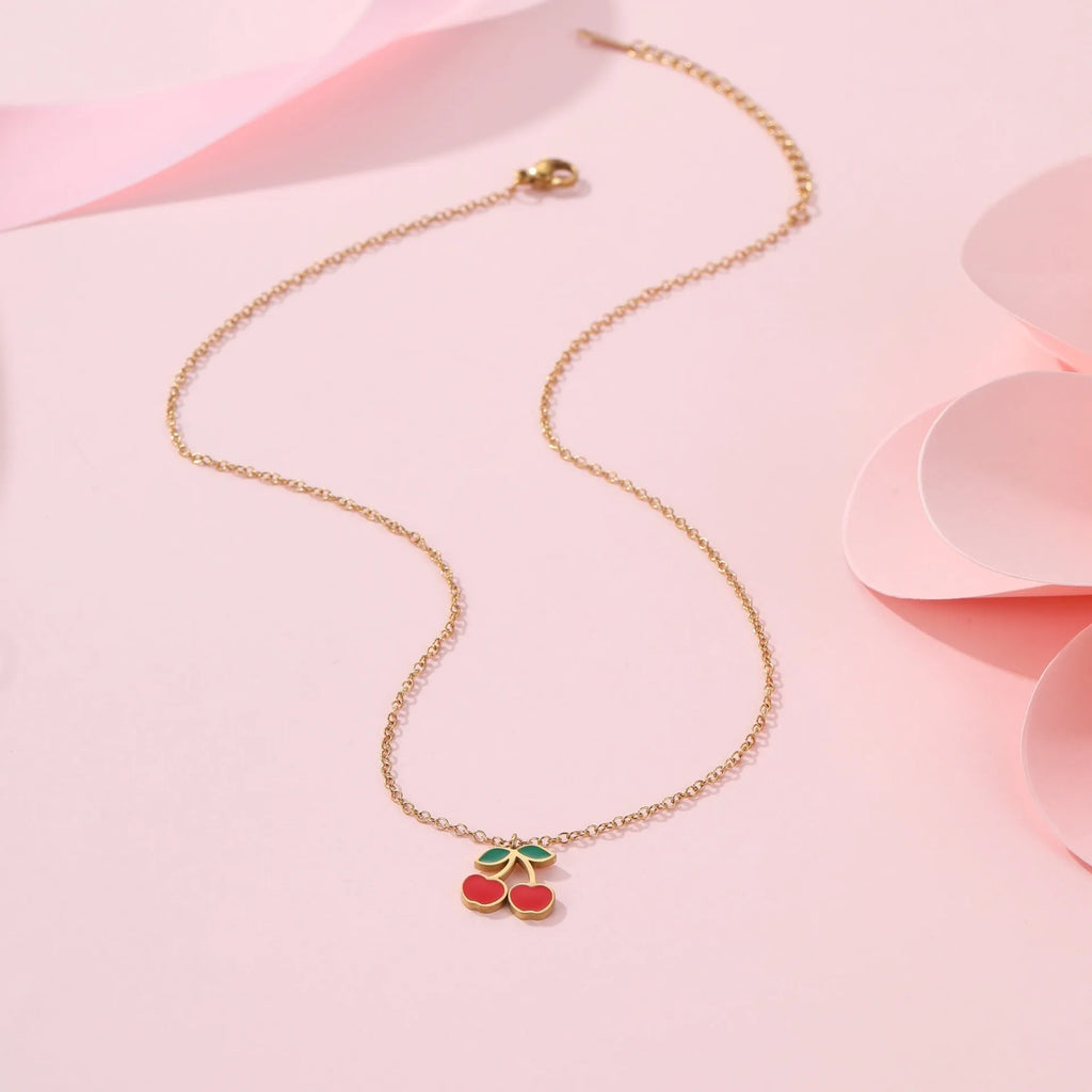 Cherry-themed jewellery set with gold-plated necklace, bracelet, earrings, and ring on stainless steel chains.