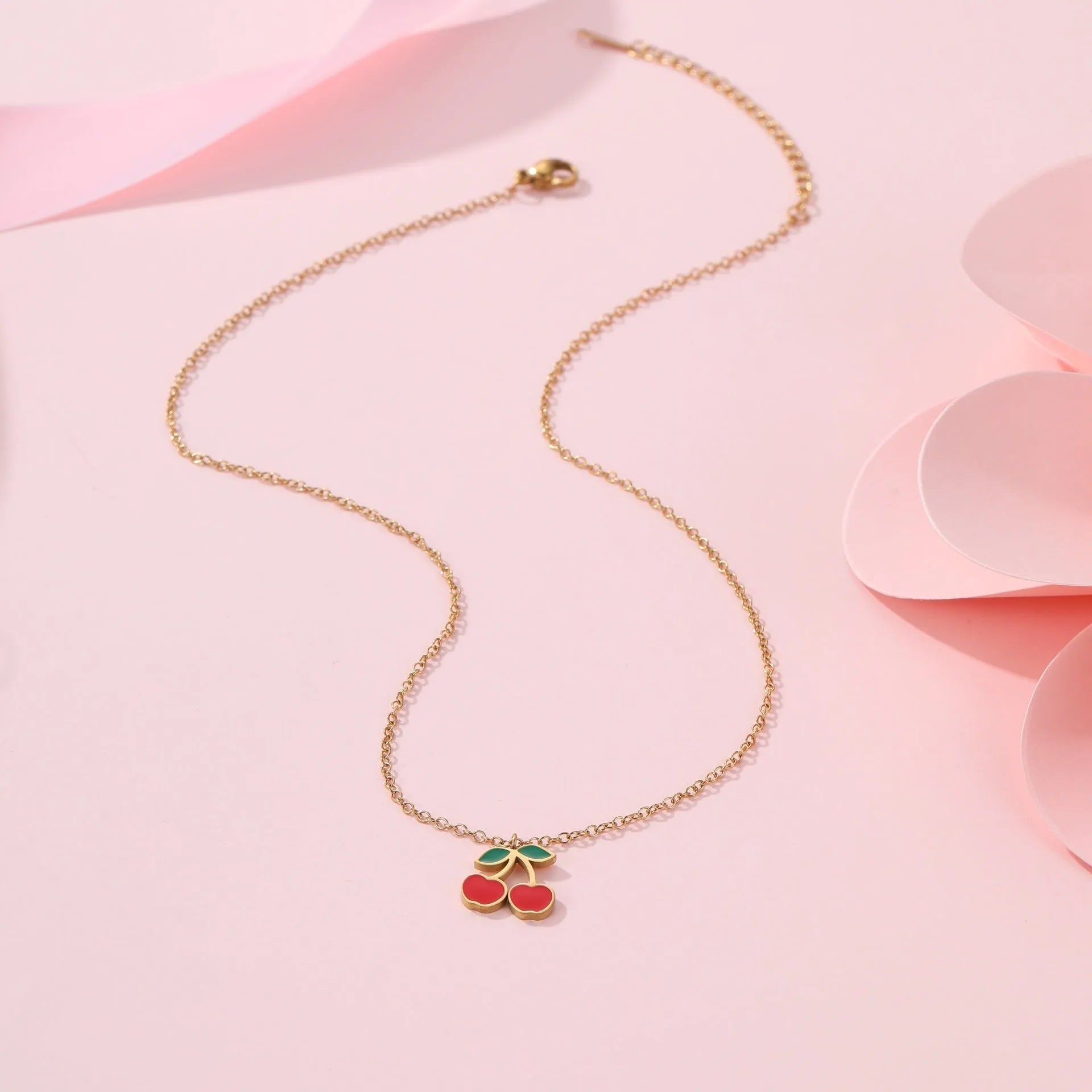 Cherry-themed jewellery set with gold-plated necklace, bracelet, earrings, and ring on stainless steel chains.