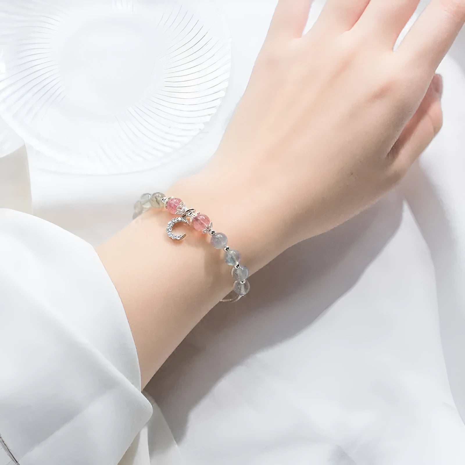 Natural moonstone bracelet with silver crescent moon charm on an adjustable chain.