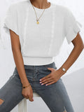 Loose-fitting white knitted pullover sweater with textured ruffled short sleeves on a model.