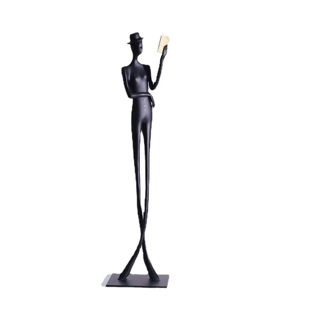 Black cast aluminium reading woman sculpture on desktop, 12 cm wide by 51 cm high