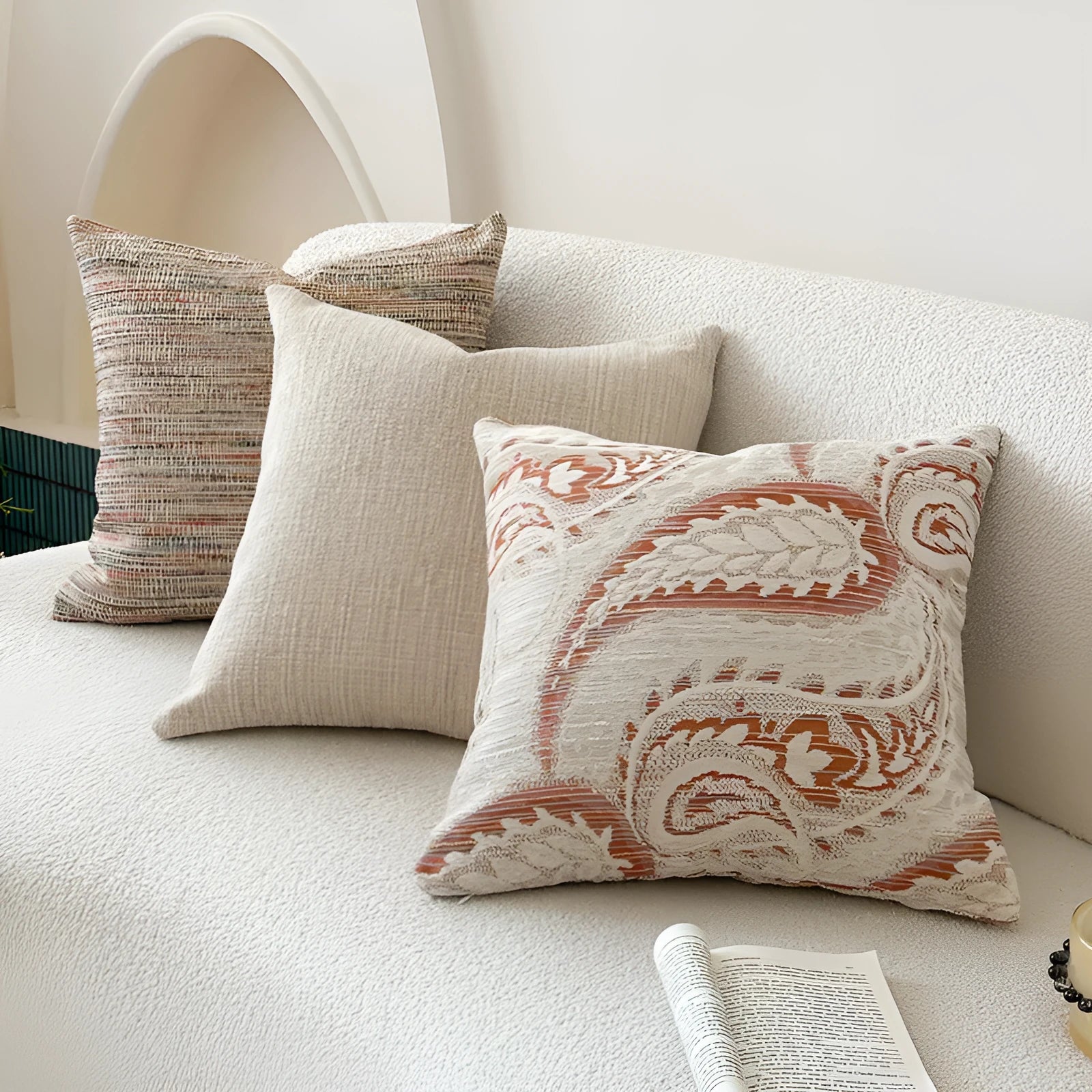 Amber-coloured jacquard pillow cover with paisley and flower pattern, shown in 45x45cm size on a sofa.