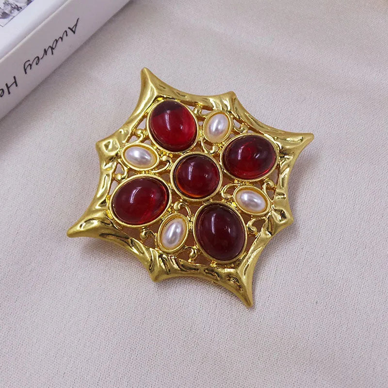 Close-up of a medieval-style baroque cross brooch with crystal decoration on a metal base.