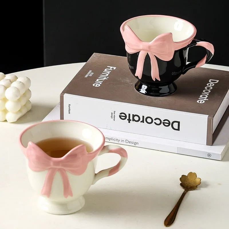 Ceramic mug with a heart and bow design in black pink and white powder colour options.