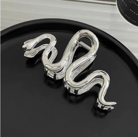 Assortment of silver metal hair claw barrettes with various designs including bows, pearls, and geometric shapes.