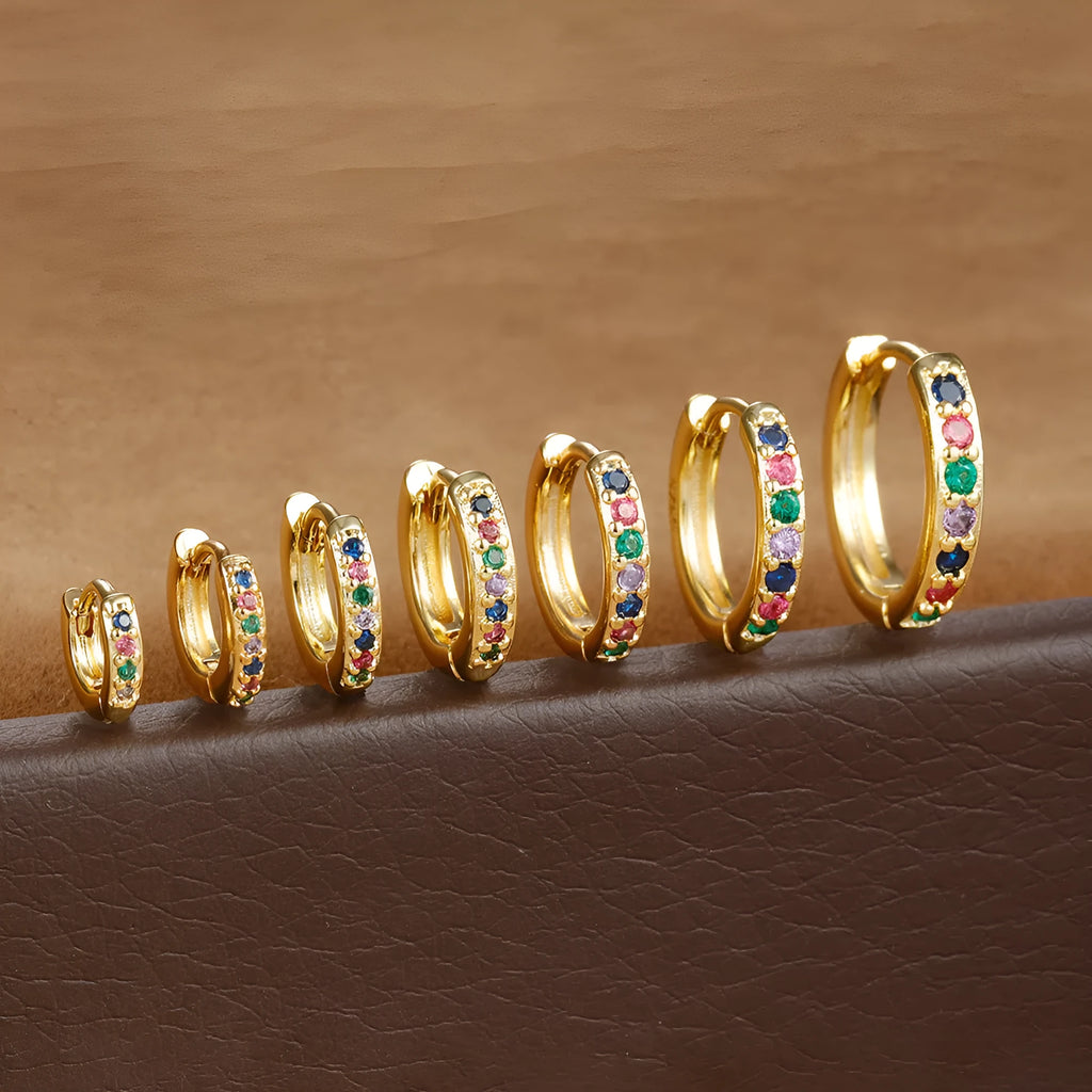 Perforated circle stud earrings with zircon detail in gold, rose gold, and silver colours on a white background.