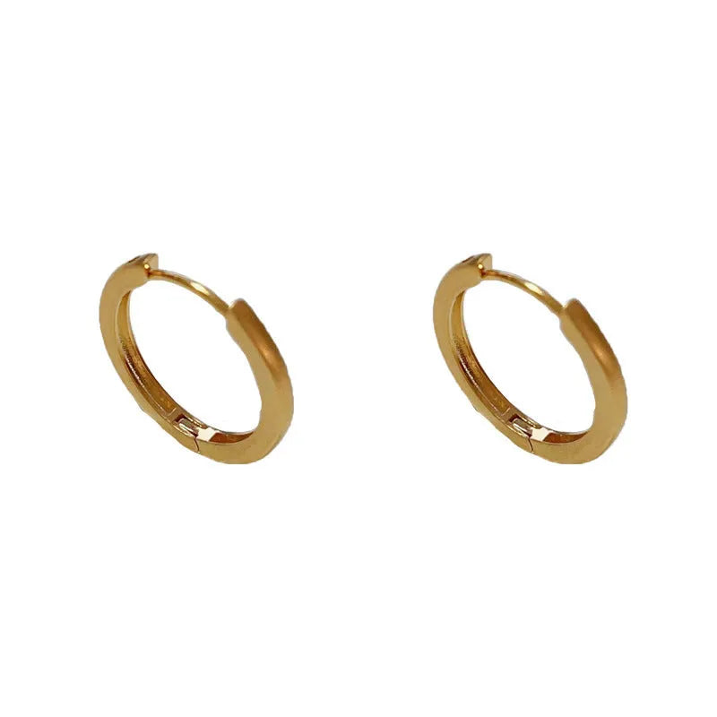 Geometric gold-plated ear clip with round eyelet detail on white background