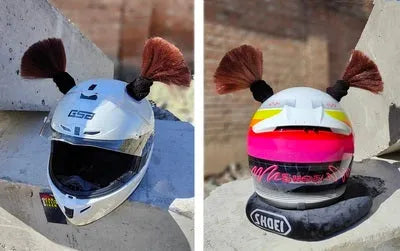 Pair of decorative braided balls for helmet customisation next to a tube of adhesive