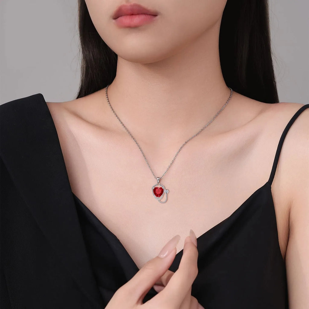 Red diamond coloured women's necklace with wings, cross, and stethoscope pendant.