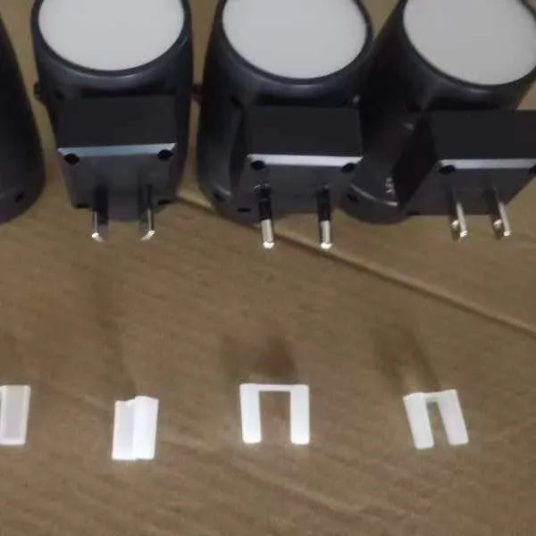 Small white induction night lamp plugged into a wall socket with a rotatable head.