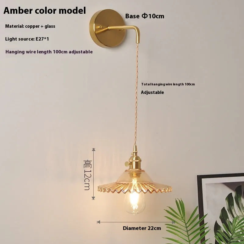 Brass lotus-shaped wall lamp with glass shade in choice of six colours on a plain wall.
