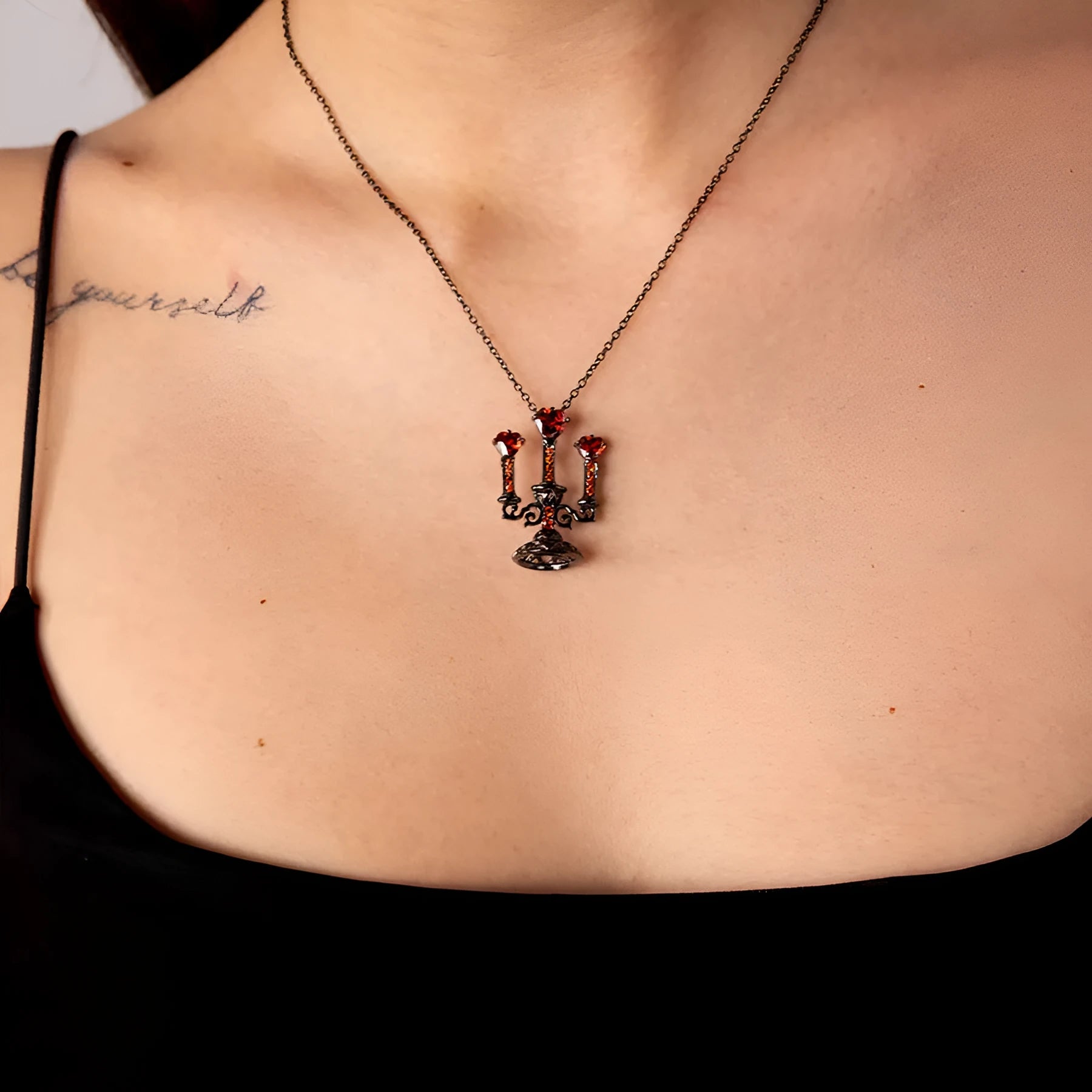 Close-up of a retro-style hollow candlestick pendant necklace with a cross chain, in a gothic design.